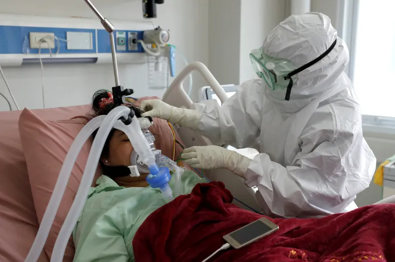 A nurse assists a patient suffering from the coronavirus disease (COVID-19) at the intensive care unit at a hospital in Bogor, Indonesia [Willy Kurniawan/Reuters]
