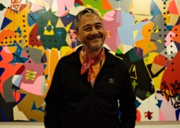 Cyril Kongo poses in front of one of his graffiti-style paintings at Art Jakarta [Jessica Washington/ Al Jazeera]