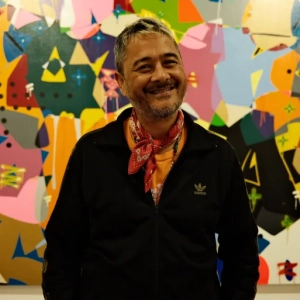 Cyril Kongo poses in front of one of his graffiti-style paintings at Art Jakarta [Jessica Washington/ Al Jazeera]