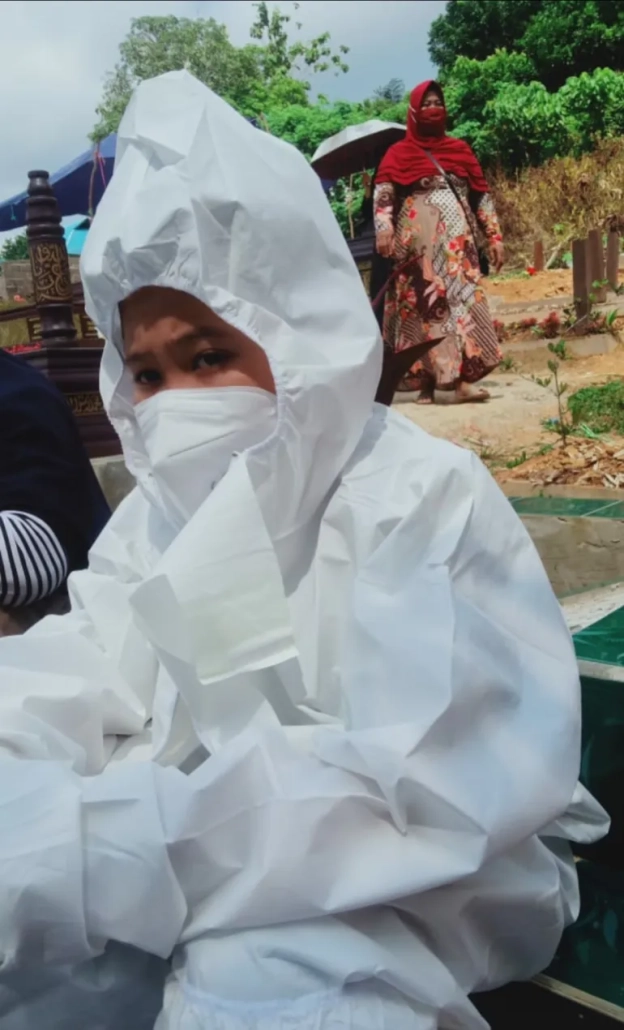 Arga, 13, sits in his hazmat suit near his parents’ graves [Supplied]