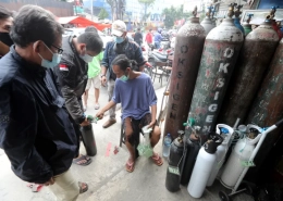 A worker checks the queue number at an oxygen refill shop in Jakarta. The surge in COVID-19 cases has led to soaring demand for oxygen [Bagus Indahono/EPA]