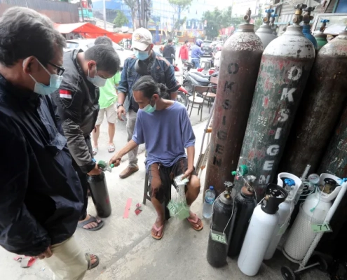 A worker checks the queue number at an oxygen refill shop in Jakarta. The surge in COVID-19 cases has led to soaring demand for oxygen [Bagus Indahono/EPA]