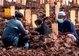 Families mourn at the graveside of a loved one lost to COVID-19 [Fakhrur Rozi/Al Jazeera]