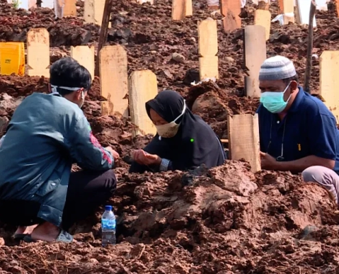 Families mourn at the graveside of a loved one lost to COVID-19 [Fakhrur Rozi/Al Jazeera]