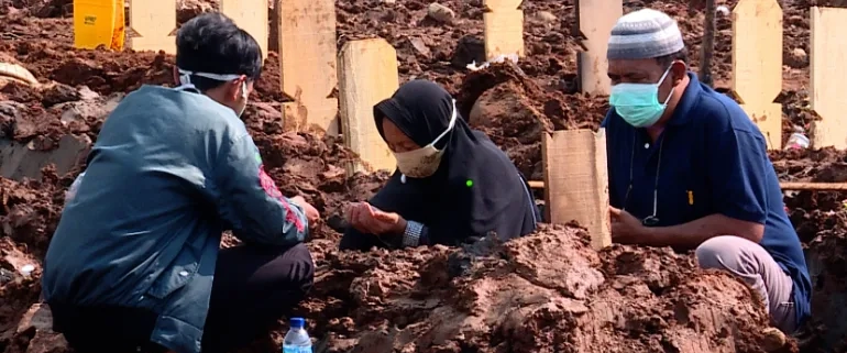 Families mourn at the graveside of a loved one lost to COVID-19 [Fakhrur Rozi/Al Jazeera]